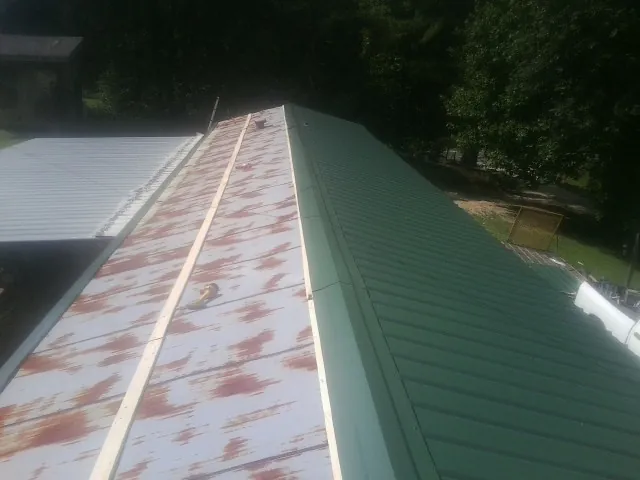 Old rusted panels beside newly installed green metal roofing — Wind Damage Roof Repair by Roofing Brothers in Georgetown